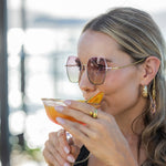 Woman enjoying a cocktail outdoors with sunglasses on