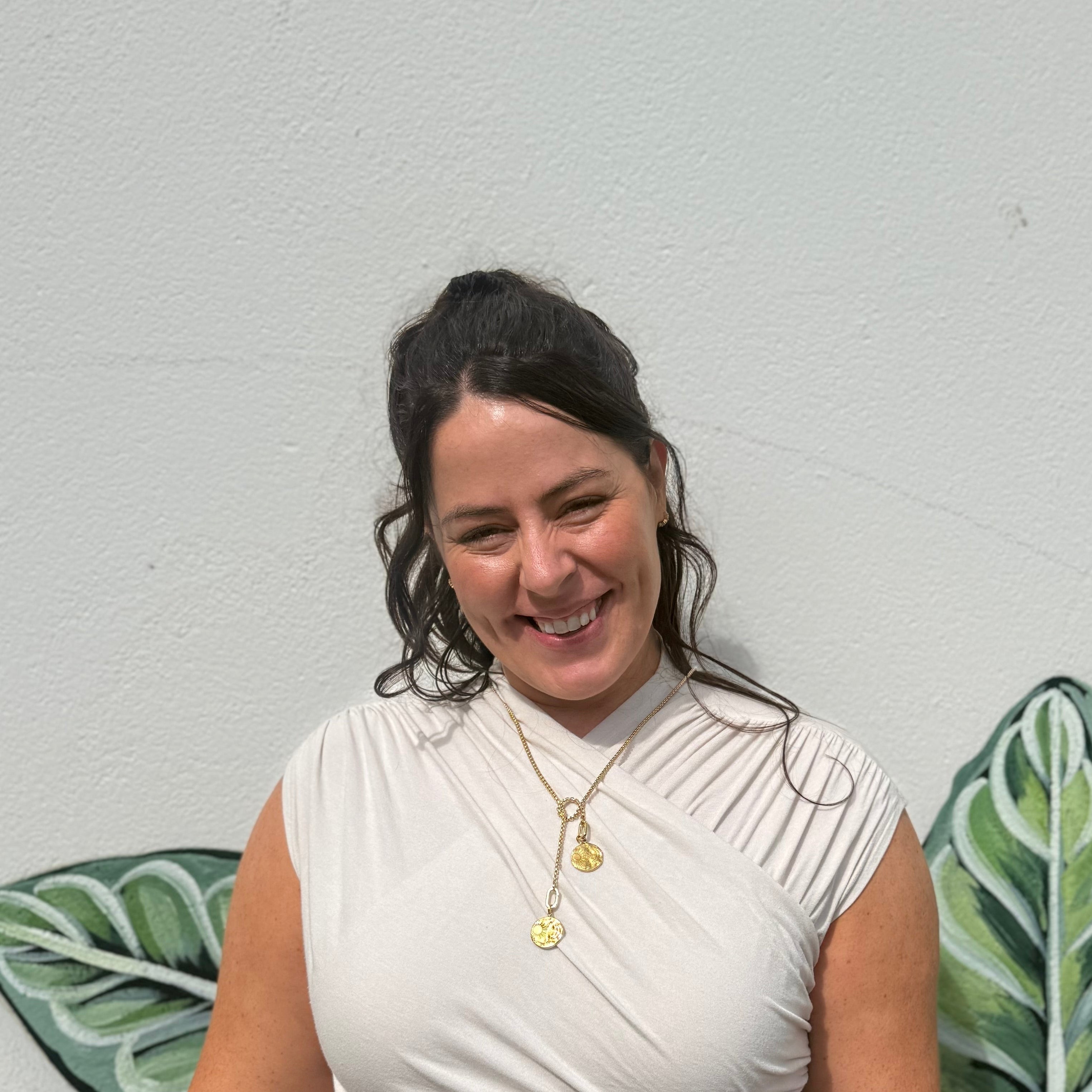 Woman standing in front of a wall with green leafy patterns
