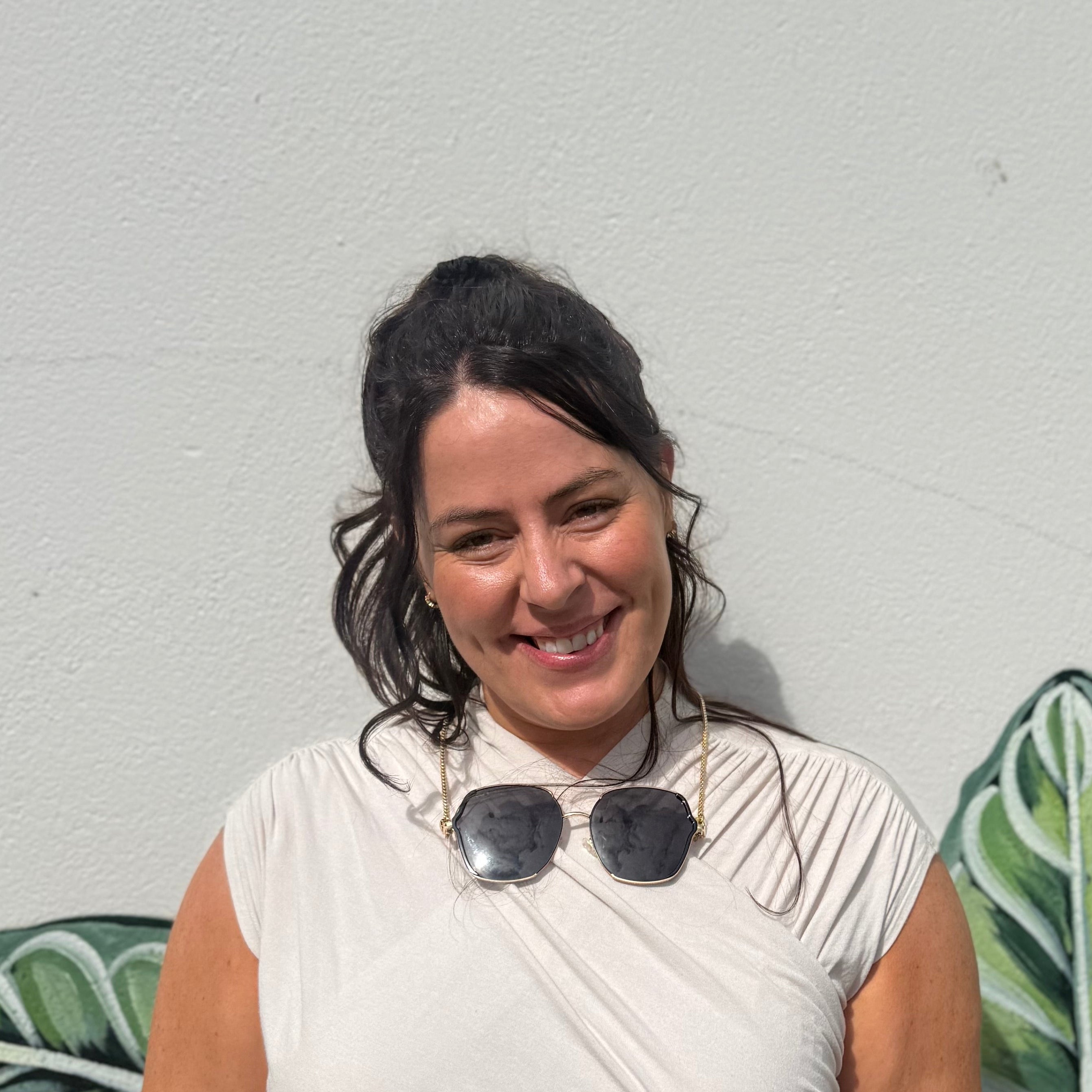 Woman standing in front of a wall with green leafy patterns wearing Ziggy Sunglasses
