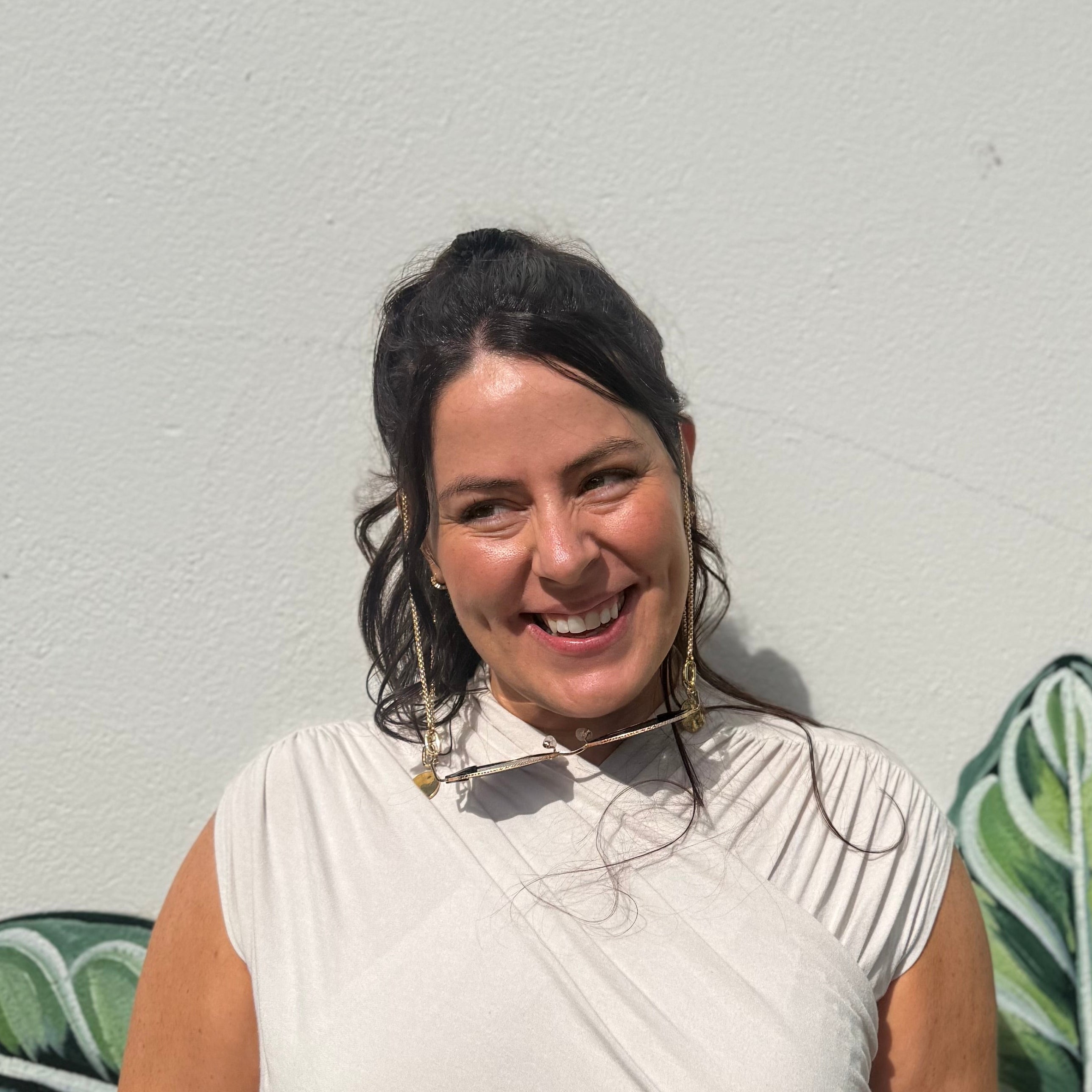 Woman standing in front of a wall with green leafy patterns